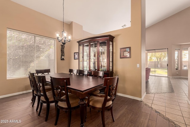 dining room featuring dark wood-type flooring, high vaulted ceiling, and an inviting chandelier