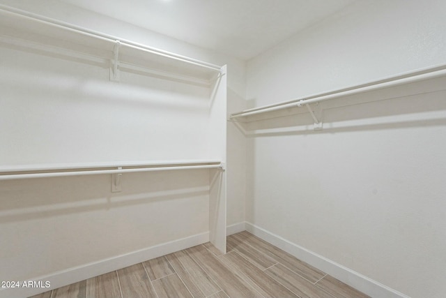 walk in closet with light hardwood / wood-style flooring