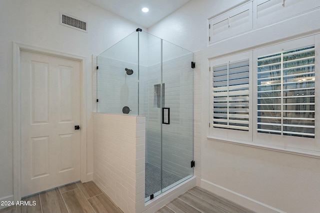 bathroom with wood-type flooring and a shower with shower door