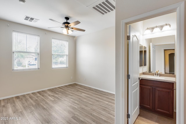9165 W Mine Trl, Peoria, AZ 85383 - unfurnished bedroom with light wood-style flooring, a sink, baseboards, connected bathroom, and a ceiling fan
