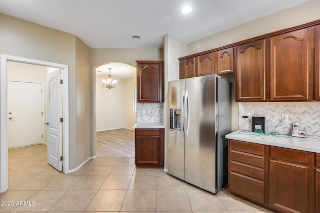 9165 W Mine Trl, Peoria, AZ 85383 - kitchen featuring stainless steel refrigerator with ice dispenser, arched walkways, backsplash, light countertops, and a chandelier