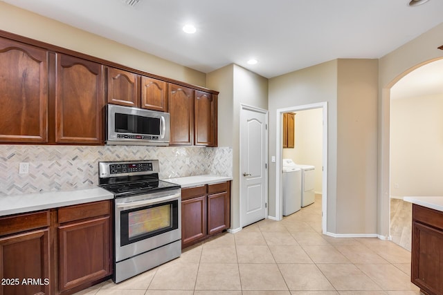 9165 W Mine Trl, Peoria, AZ 85383 - kitchen featuring appliances with stainless steel finishes, separate washer and dryer, arched walkways, backsplash, and light countertops
