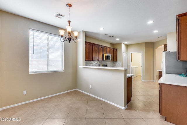 9165 W Mine Trl, Peoria, AZ 85383 - kitchen featuring appliances with stainless steel finishes, arched walkways, decorative backsplash, light countertops, and a chandelier