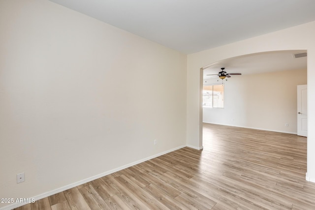 9165 W Mine Trl, Peoria, AZ 85383 - empty room with arched walkways, a ceiling fan, light wood-type flooring, and baseboards