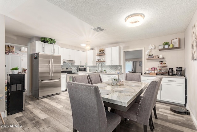 6802 S 47th St, Phoenix, AZ 85042 - dining room featuring light wood-style floors and a textured ceiling