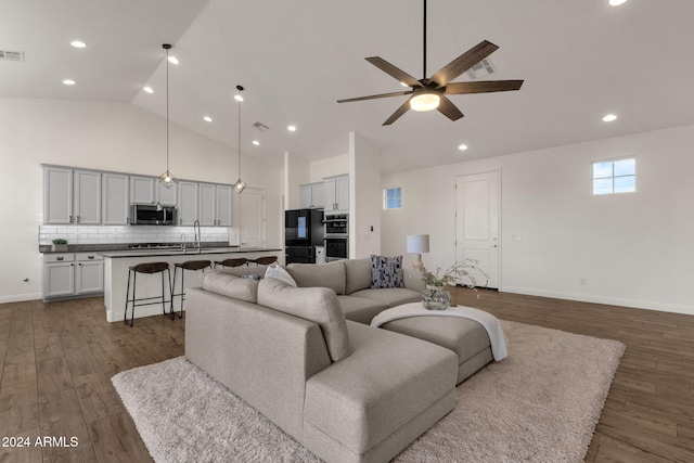 living room featuring dark hardwood / wood-style flooring, high vaulted ceiling, sink, and ceiling fan