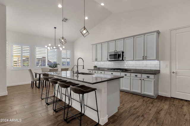 kitchen featuring an island with sink, hanging light fixtures, dark hardwood / wood-style floors, and appliances with stainless steel finishes