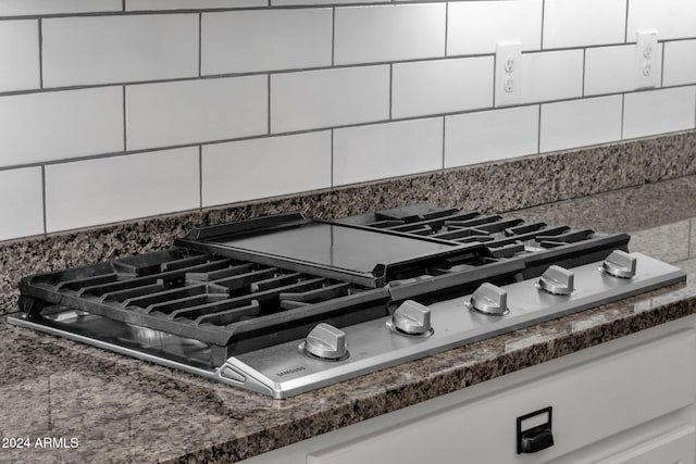 interior details with tasteful backsplash, white cabinetry, and stainless steel gas cooktop