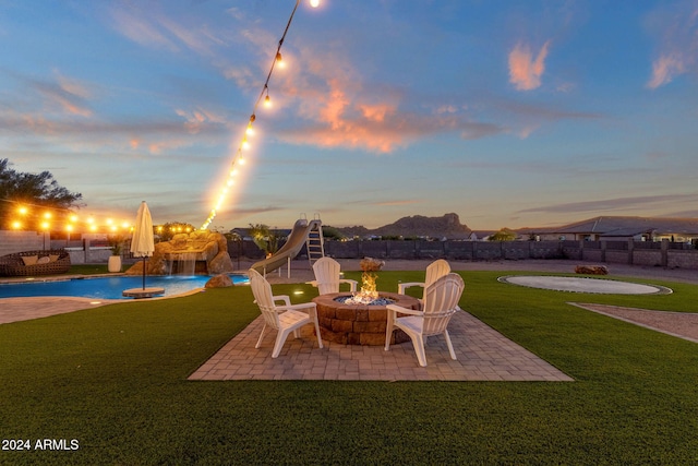 patio terrace at dusk with a lawn and a fire pit