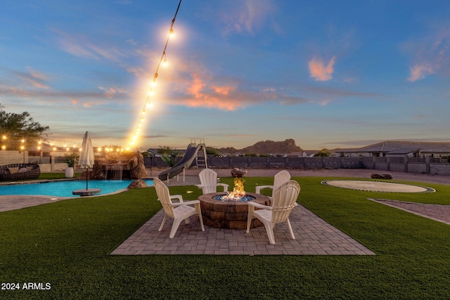 patio terrace at dusk featuring a lawn and an outdoor fire pit