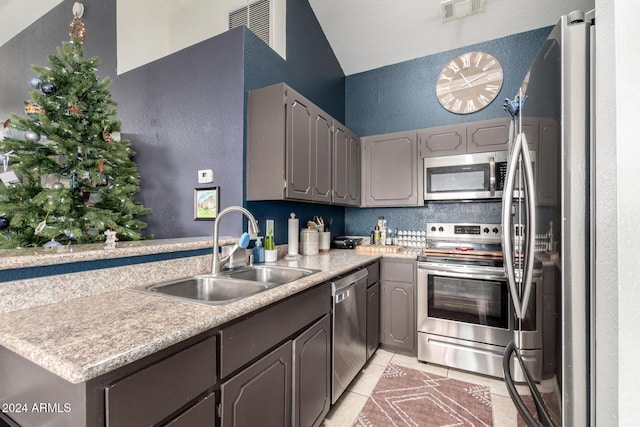 kitchen with sink, kitchen peninsula, gray cabinets, light tile patterned floors, and appliances with stainless steel finishes