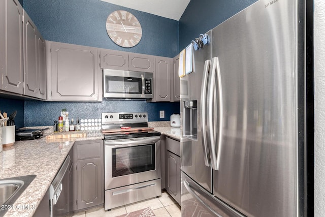 kitchen with gray cabinets, light tile patterned floors, and appliances with stainless steel finishes