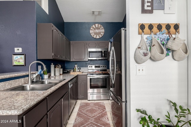 kitchen featuring sink, light tile patterned floors, stainless steel appliances, and a textured ceiling