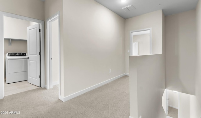 hallway featuring washer / clothes dryer and light colored carpet