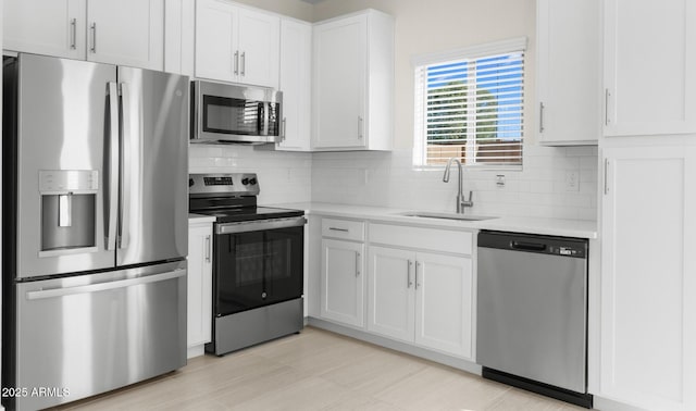 kitchen featuring stainless steel appliances, sink, white cabinets, and backsplash