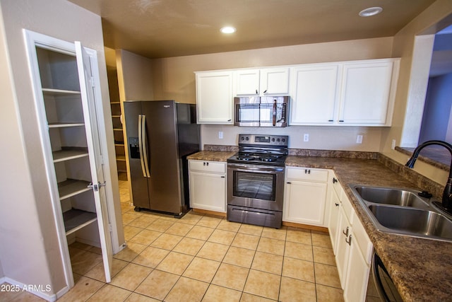 44944 W Miramar Rd, Maricopa, AZ 85139 - kitchen with stainless steel appliances, a sink, white cabinetry, light tile patterned floors, and dark countertops
