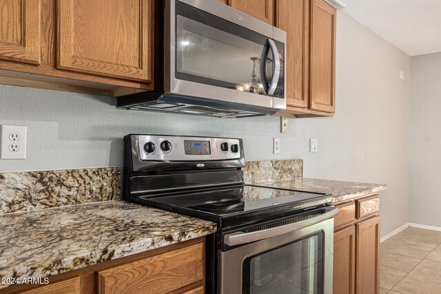 kitchen featuring light stone countertops, appliances with stainless steel finishes, and light tile patterned flooring