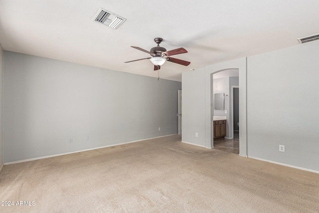 unfurnished bedroom with connected bathroom, ceiling fan, and light carpet