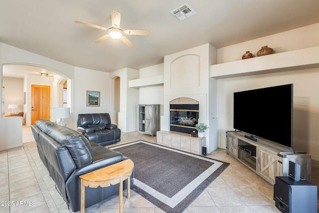 living room with light tile patterned floors, a tile fireplace, and ceiling fan