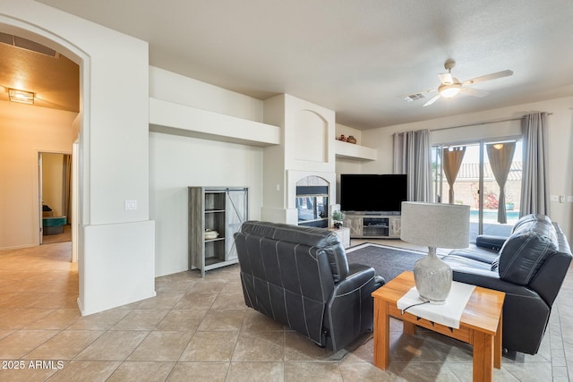 tiled living room featuring ceiling fan and a multi sided fireplace