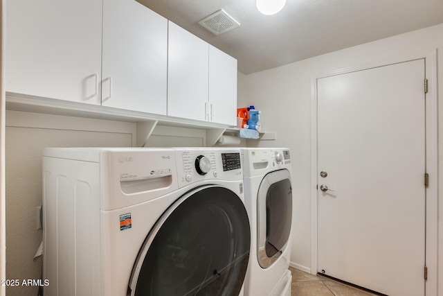 laundry area featuring cabinets, washing machine and dryer, and light tile patterned floors