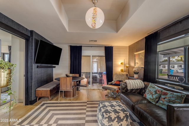 living room featuring light hardwood / wood-style flooring and a tray ceiling