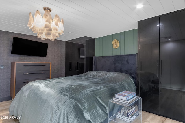 bedroom with light hardwood / wood-style floors, an inviting chandelier, and wooden ceiling