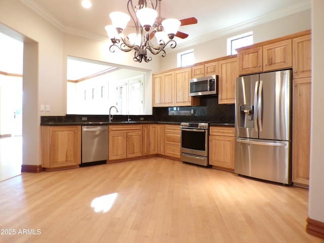 kitchen with light wood-type flooring, ornamental molding, appliances with stainless steel finishes, pendant lighting, and backsplash