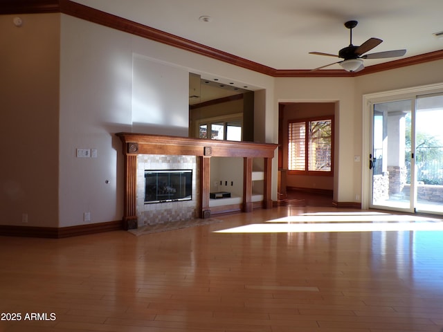 unfurnished living room with hardwood / wood-style flooring, ornamental molding, ceiling fan, and a fireplace