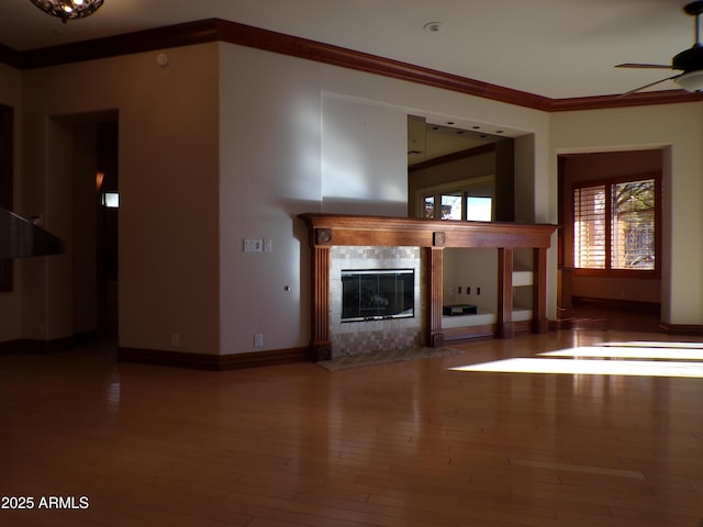 unfurnished living room with hardwood / wood-style flooring, ornamental molding, a tile fireplace, and ceiling fan