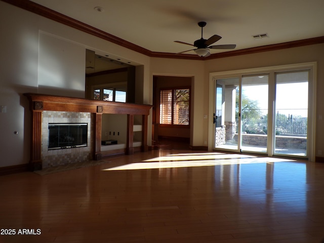 doorway to outside with a healthy amount of sunlight, ornamental molding, hardwood / wood-style floors, and a tile fireplace