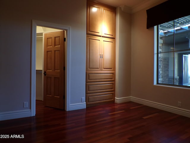 unfurnished bedroom featuring crown molding and dark wood-type flooring