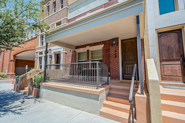 view of exterior entry with a porch and brick siding