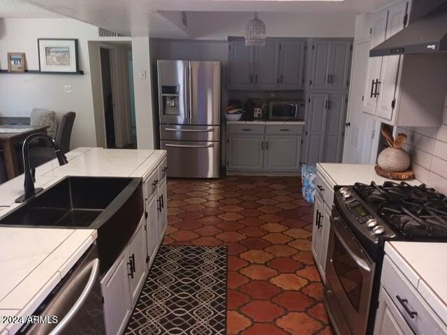 5539 N 31st Ln, Phoenix, AZ 85017 - kitchen featuring appliances with stainless steel finishes, wall chimney exhaust hood, light countertops, a sink, and decorative backsplash
