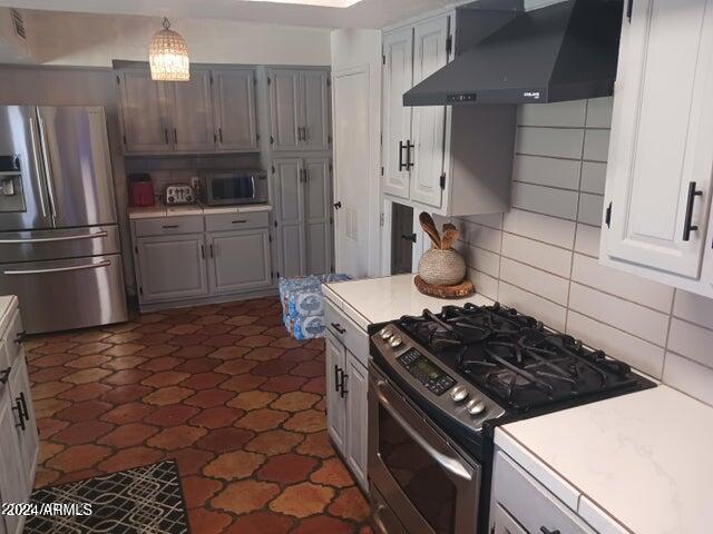 5539 N 31st Ln, Phoenix, AZ 85017 - kitchen with appliances with stainless steel finishes, wall chimney range hood, light countertops, decorative backsplash, and gray cabinets