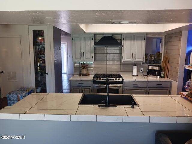 5539 N 31st Ln, Phoenix, AZ 85017 - kitchen featuring premium range hood, stainless steel gas stove, tile counters, and gray cabinets