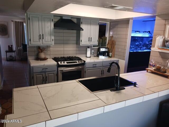 5539 N 31st Ln, Phoenix, AZ 85017 - kitchen featuring stainless steel gas range, custom range hood, tile counters, tasteful backsplash, and a sink