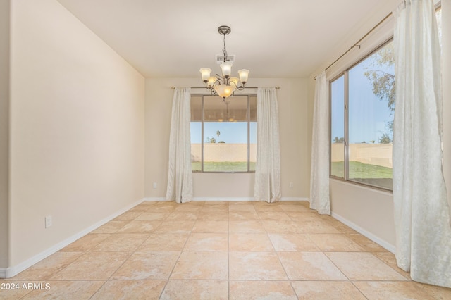 spare room featuring a healthy amount of sunlight, light tile patterned floors, and an inviting chandelier