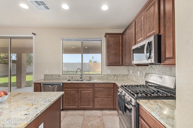 kitchen with stainless steel appliances, light stone countertops, sink, and plenty of natural light