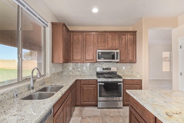 kitchen featuring light stone counters, sink, backsplash, and appliances with stainless steel finishes