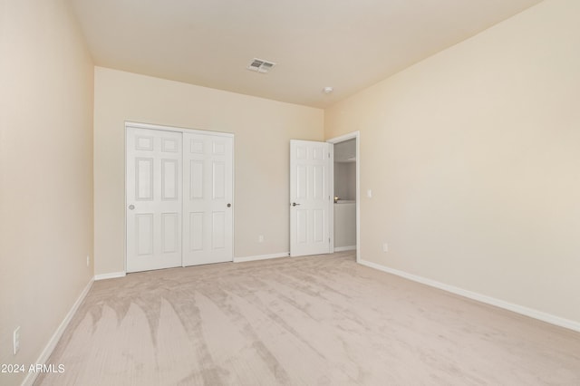 unfurnished bedroom featuring light carpet and a closet