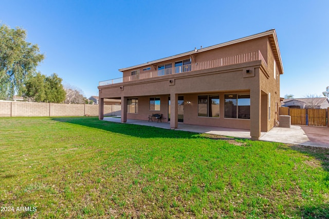 back of property featuring a balcony, a patio, and a lawn