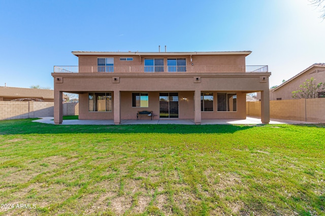 back of property featuring a balcony, a lawn, and a patio area