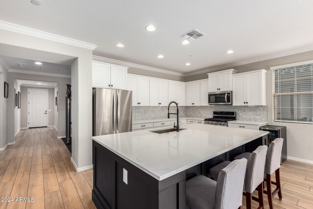 kitchen with a center island with sink, light hardwood / wood-style flooring, sink, and appliances with stainless steel finishes