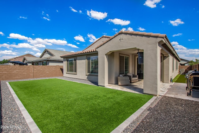 back of property with a lawn and a patio area