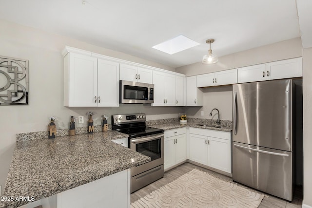 5649 W Holly St, Phoenix, AZ 85035 - kitchen featuring appliances with stainless steel finishes, a skylight, white cabinetry, and light wood-type flooring