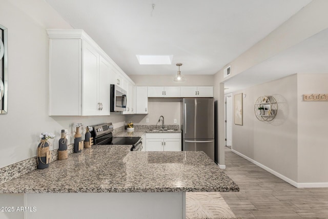 5649 W Holly St, Phoenix, AZ 85035 - kitchen featuring stainless steel appliances, a skylight, light stone countertops, and light wood-style flooring
