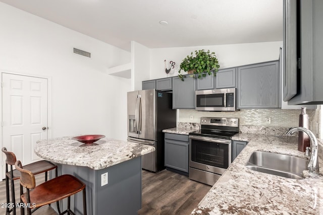 8648 W Fargo Dr, Peoria, AZ 85382 - kitchen featuring a sink, visible vents, gray cabinetry, stainless steel appliances, and a kitchen bar