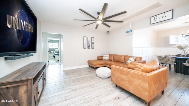 living room featuring a healthy amount of sunlight, ceiling fan with notable chandelier, and light hardwood / wood-style floors