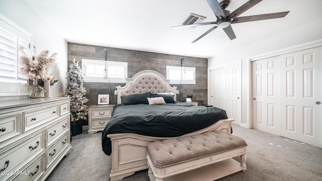 carpeted bedroom featuring multiple closets and ceiling fan